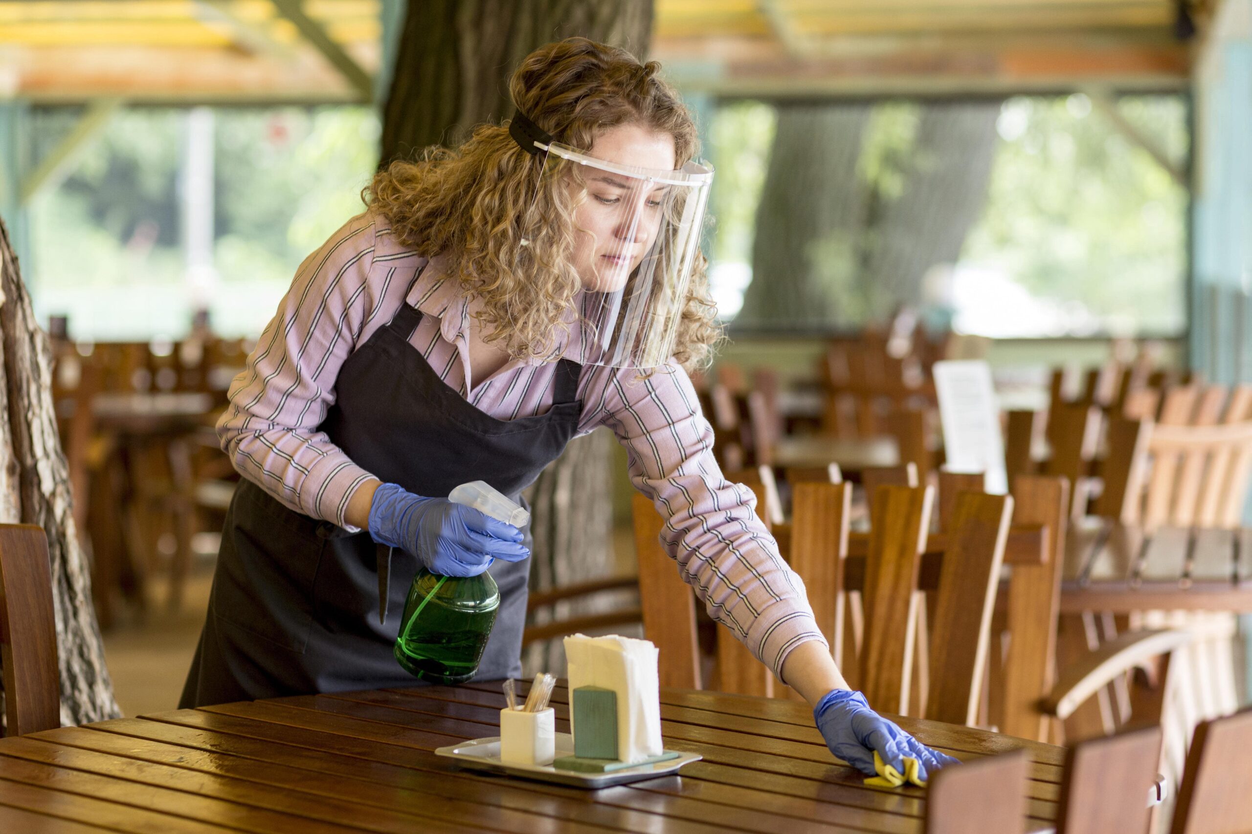 AS Auto Nettoyage désinfecte une terrasse de café à Bordeaux, femme protège et nettoie une table en plein air,